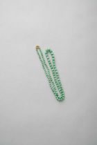 A CHINESE APPLE GREEN JADEITE GRADUATED NECKLACE 20TH CENTURY Formed of 104 graduated beads joined