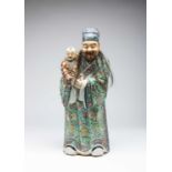 A LARGE CHINESE FAMILLE ROSE FIGURE OF AN IMMORTAL AND CHILD LATE QING DYNASTY The bearded figure
