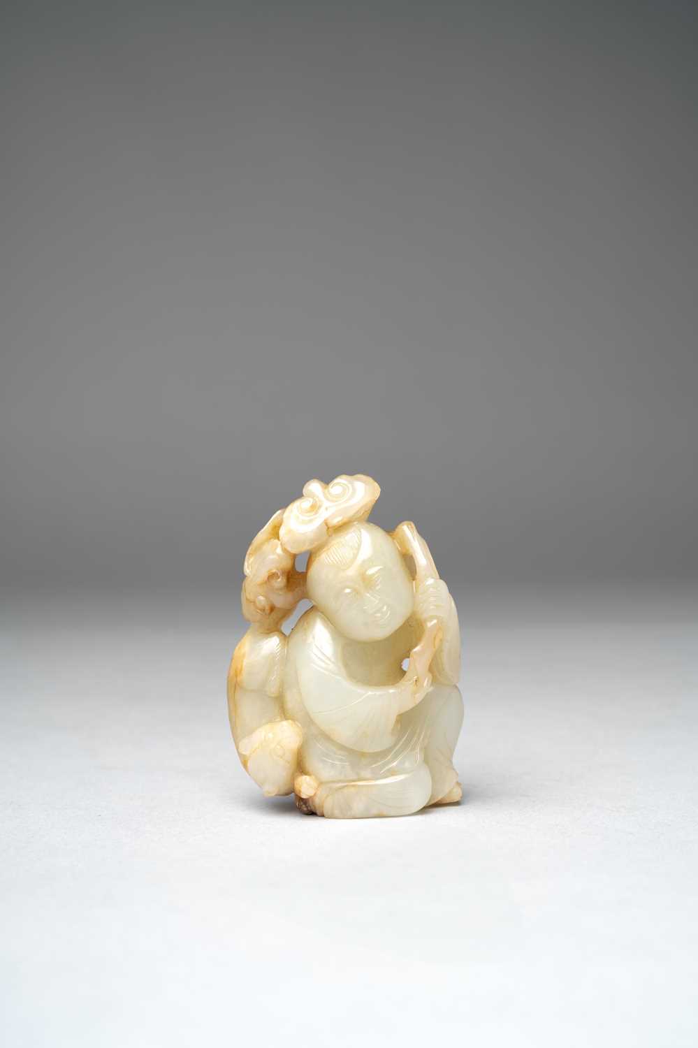 A CHINESE PALE CELADON CARVING OF A BOY AND A BADGER QING DYNASTY Depicting a kneeling boy holding a