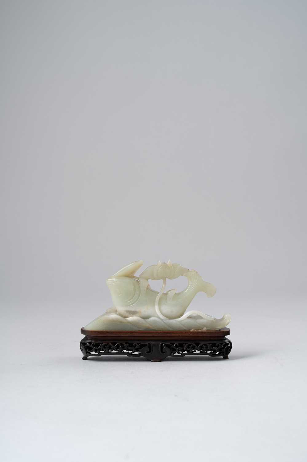 A CHINESE CELADON JADE CARVING OF A CARP QING DYNASTY Emerging from rolling waves, its upturned body