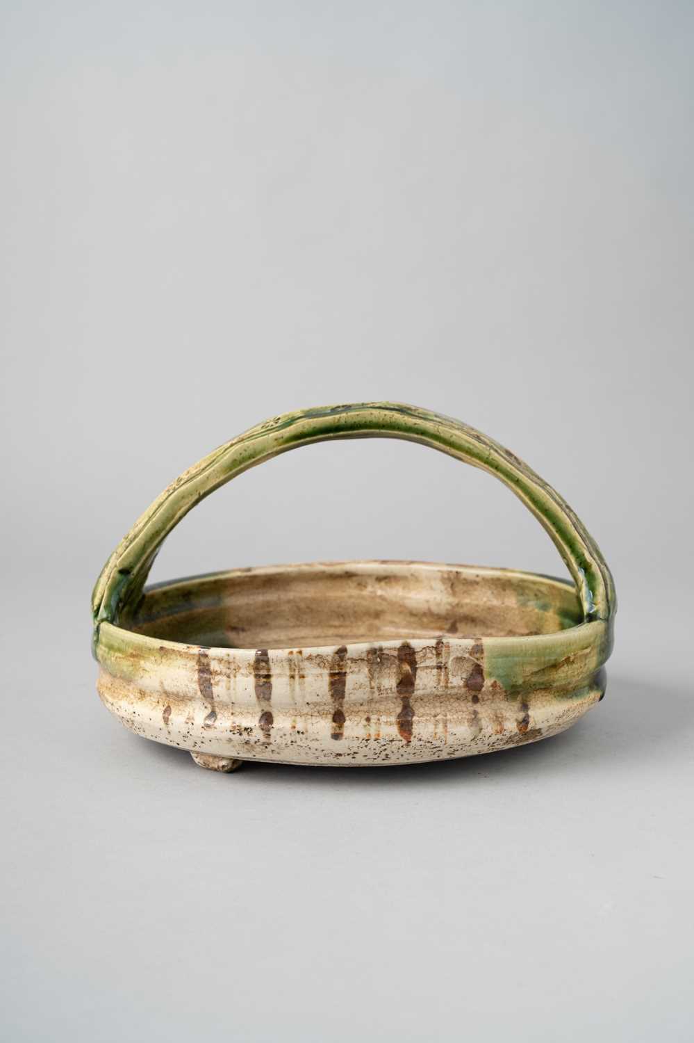 A JAPANESE ORIBE WARE BASKET MEIJI ERA, 19TH/20TH CENTURY Of irregular shape with a tall loop