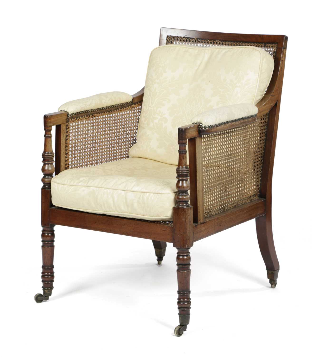 A REGENCY MAHOGANY BERGÈRE ARMCHAIR EARLY 19TH CENTURY with a cane back, seat and sides and later