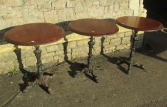 Three pub tables, the circular wooden tops 62 cm diameter raised on cast iron bases with swept paw