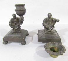 Two single bronze candlesticks of a Chinese man holding a single sconce, (both as found)