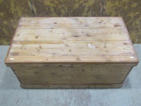 An antique stripped pine box with hinged boarded lid, 45 cm high x 99 cm wide x 53 cm deep