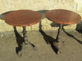 Pair of circular wooden topped pub tables raised on cast iron bases with entwined stylised dolphin