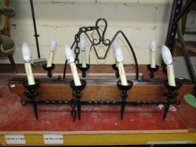 A gothic style ceiling light in oak and wrought iron bearing eight sconces, 110 cm length x 55 cm