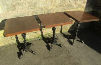 Three wooden topped pub tables with canted corners raised on cast iron bases with swept paw feet,