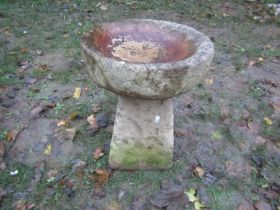 A weathered composition stone bird bath of circular form raised on a square tapered base, 39cm