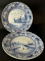 Pair of Delft chargers, each with an individual hand painted landscape panel, set within repeating