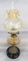 A Victorian oil lamp with an amber font and crimped glass shade. 69cm high approx.