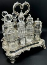 A Victorian silver table condiment stand with eight glass bottles, the oblong scrolled stand is