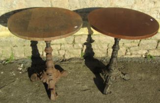 Pair of circular wooden topped pub tables raised on cast iron bases with entwined stylised dolphin