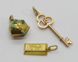 Three small gold charms / pendants comprising a 9k ingot, a 9ct 18th birthday key and a bell set