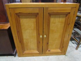 A pine side cupboard enclosed by a pair of rectangular panelled doors, 102cm wide, 36cm deep,