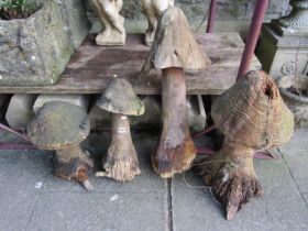 Four weathered forestry chainsaw art garden ornaments in the form of mushrooms/toadstools of varying