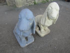 A matched pair of painted cast composition stone garden ornaments in the form of seated basset