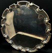 A silver scalloped edge salver, raised on scrolled supports, 30cm diam, Sheffield 1922 maker William