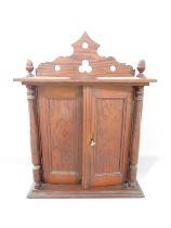 A Victorian pitch pine cabinet, with acorn finials to the cornice over two panelled doors flanked by