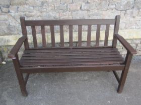 A stained teak two seat garden bench with slatted seat and back 127 cm wide
