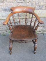 An antique stained elm and beechwood smokers bow elbow chair with turned spindle back and saddle