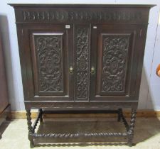 Edwardian oak cabinet enclosed by two carved and panelled doors with open framework on barley