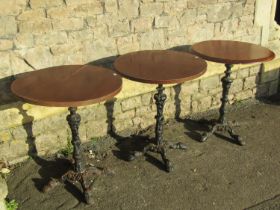Three circular wooden topped pub tables raised on cast iron bases with swept paw feet, the tops