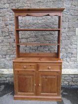A small pine kitchen dresser, fitted with two drawers and a pair of panelled doors, below delft rack
