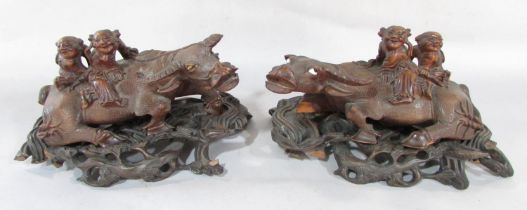 A pair of Chinese carved hardwood water buffalo being ridden two boys, both on stands, (as found).