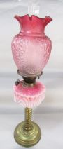 An antique brass column oil lamp with faded pink font and pink etched glass shade, 82cm high approx.