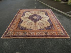 A Persian style carpet with blue medallion centre upon a beige ground within a trailing floral