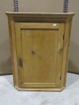 A 19th century stripped pine hanging corner cupboard enclosed by rectangular panelled door with