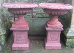 A pair of cast composition stone garden urns, the flared squat circular lobbed bowls with flared egg