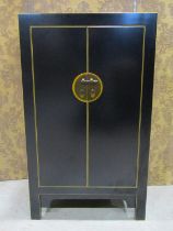 A contemporary Chinese black lacquered low side cupboard enclosed by a pair of doors with shelved