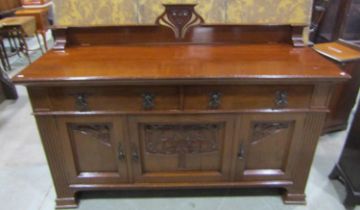 A large art nouveau oak sideboard with carved organic detail with three doors beneath two drawers,