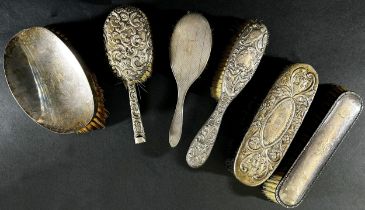 Six assorted silver backed dressing table brushes and a cut glass bottle with a sterling collar,