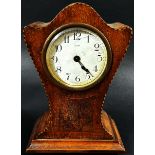 An Edwardian mahogany mantle clock with shaped outline, chequered string borders and eight day