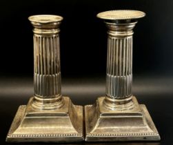 A pair of small reeded silver column candlesticks raised on a platform base (one lacking a sconce)
