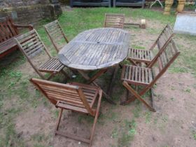 A weathered contemporary teak garden table of oval form with slatted top, raised on X framed
