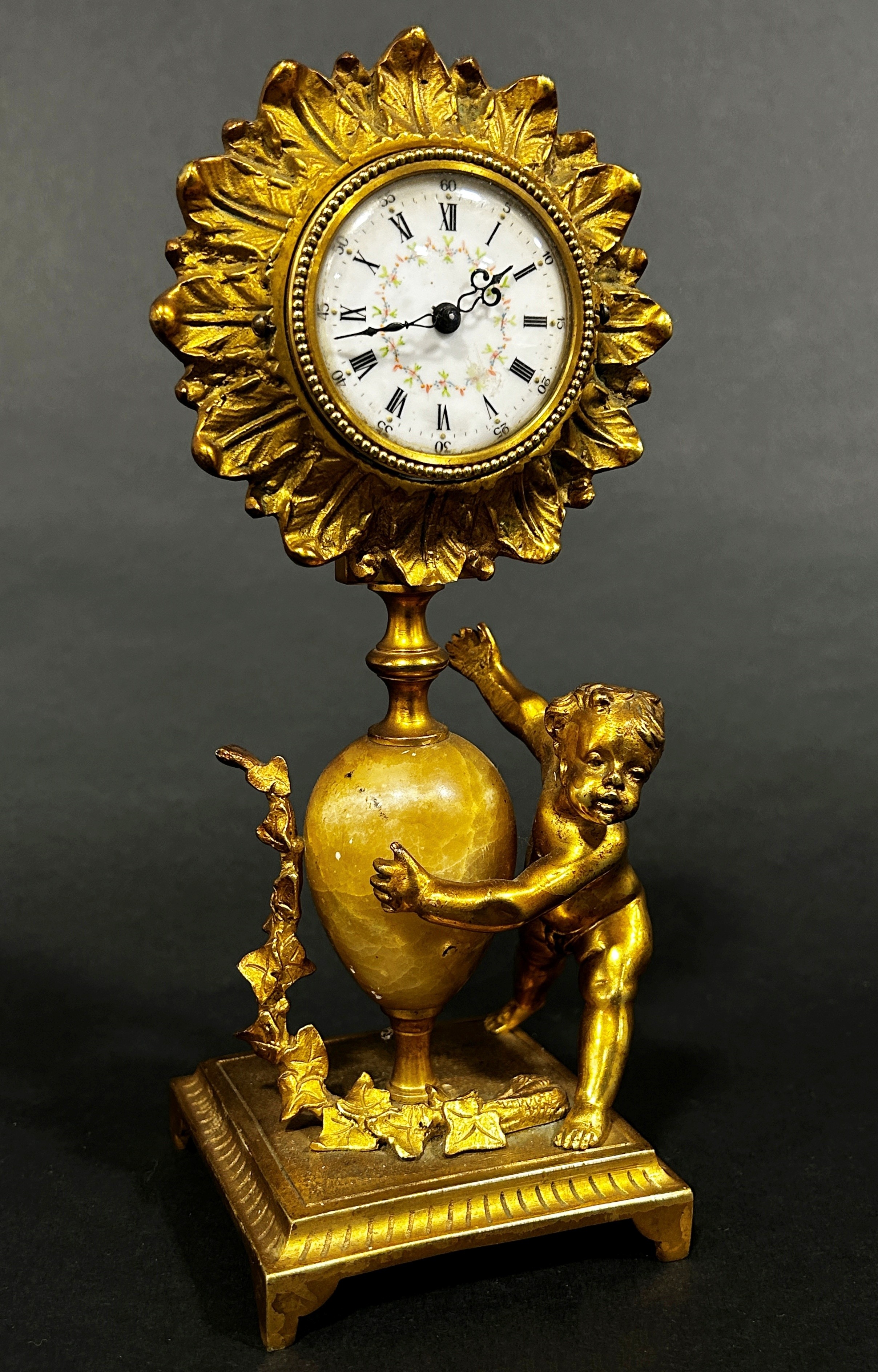 19th century gilt mantle clock the painted dial within a flower head border, surmounted on an onyx