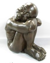 A bronze effect resin study of a naked figure, sleeping on arms resting on drawn up knees, 34cm high