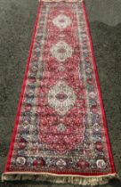 A Kashmir runner with a full pile red ground, 300cm x 80cm