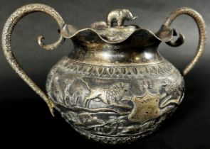 A middle eastern silver metal bowl with cover and serpent handles decorated with lions, gazelles and