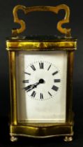 A brass carriage clock set within a shaped case with enamelled dial and eight day timepiece,