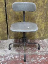 A vintage industrial office chair with adjustable base, raised on tubular supports