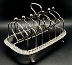 A George III silver toast rack with six heart shaped divisions, gadrooned base on scrolled feet,