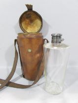 An early 20th century glass flask with a plated screw top cap, in a leather case with shoulder