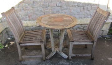 A small weathered teak terrace table with circular slatted top raised on tapered supports united