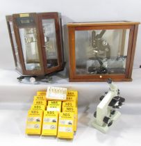 A microscope in a glass isolation chamber, a mid 20th century laboratory microscope and a set of