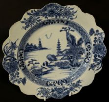 A Chinese blue and white export plate with scalloped edge with pagoda, landscape and floral detail